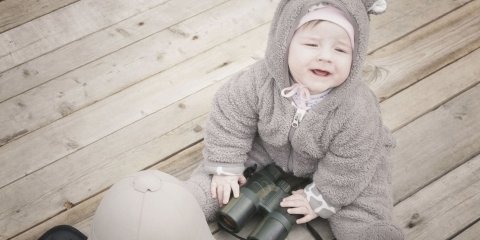 Toddler in a cute onesie with binoculars