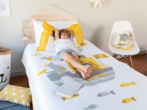 Purdy the Penguin Organic Kids Bedding picture showing child stretched out on the bed with legs crossed